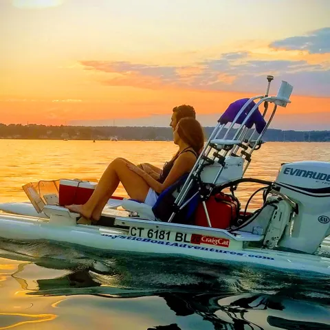 Mini powerboats on the water near a lighthouse at sunset