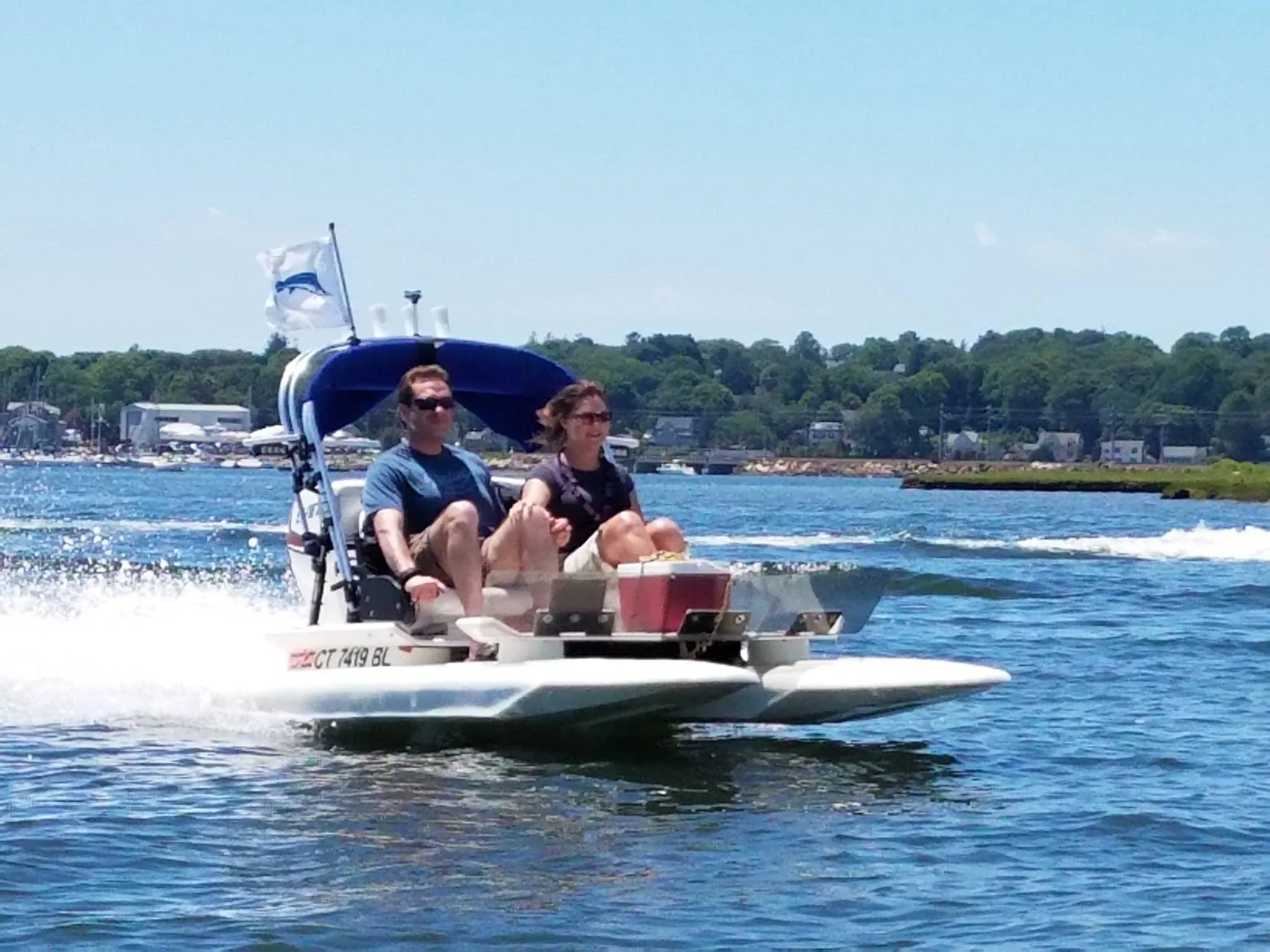 Two guests riding a mini powerboat on the water at golden hour